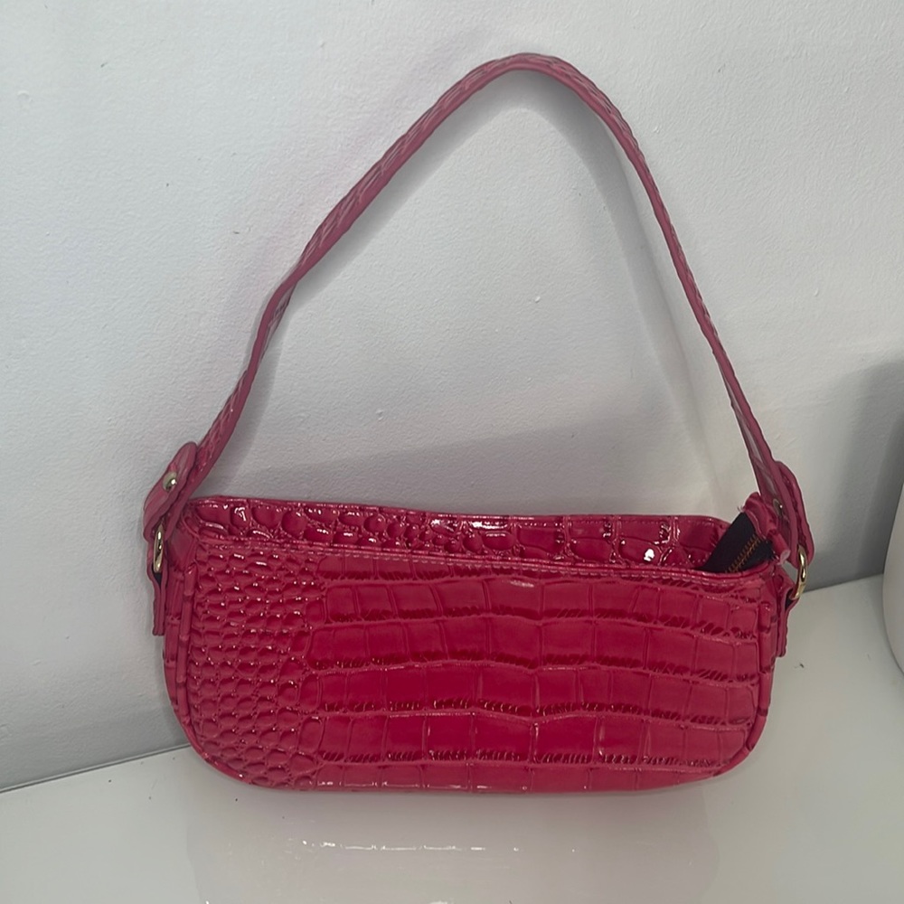 This bag is a cute pink shoulder bag. It's very spacious with gold detailing.